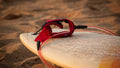 Exploring the Pro Hunter Surf Tackle Kit 65Pc with red surfboard leash on sandy beach.