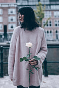 woman in white sweater holding white flower