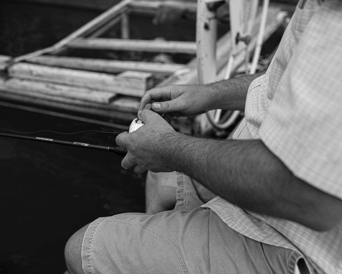 Fishing enthusiast preparing bait cotton in fishing tactics on a boat by the water.