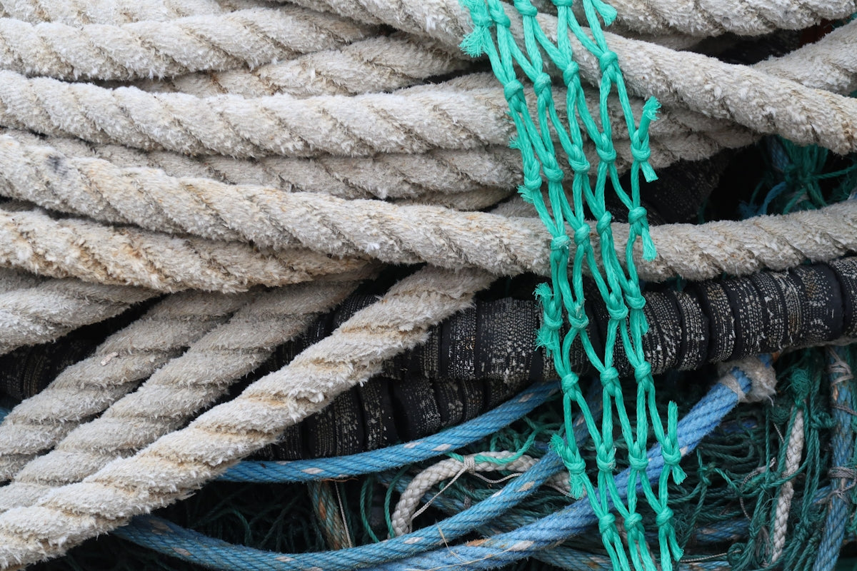 Close-up of green nylon mesh intertwined with various ropes and nets, showcasing durability and versatility in marine use.