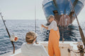 two person in fishing boat near cargo ship during daytime