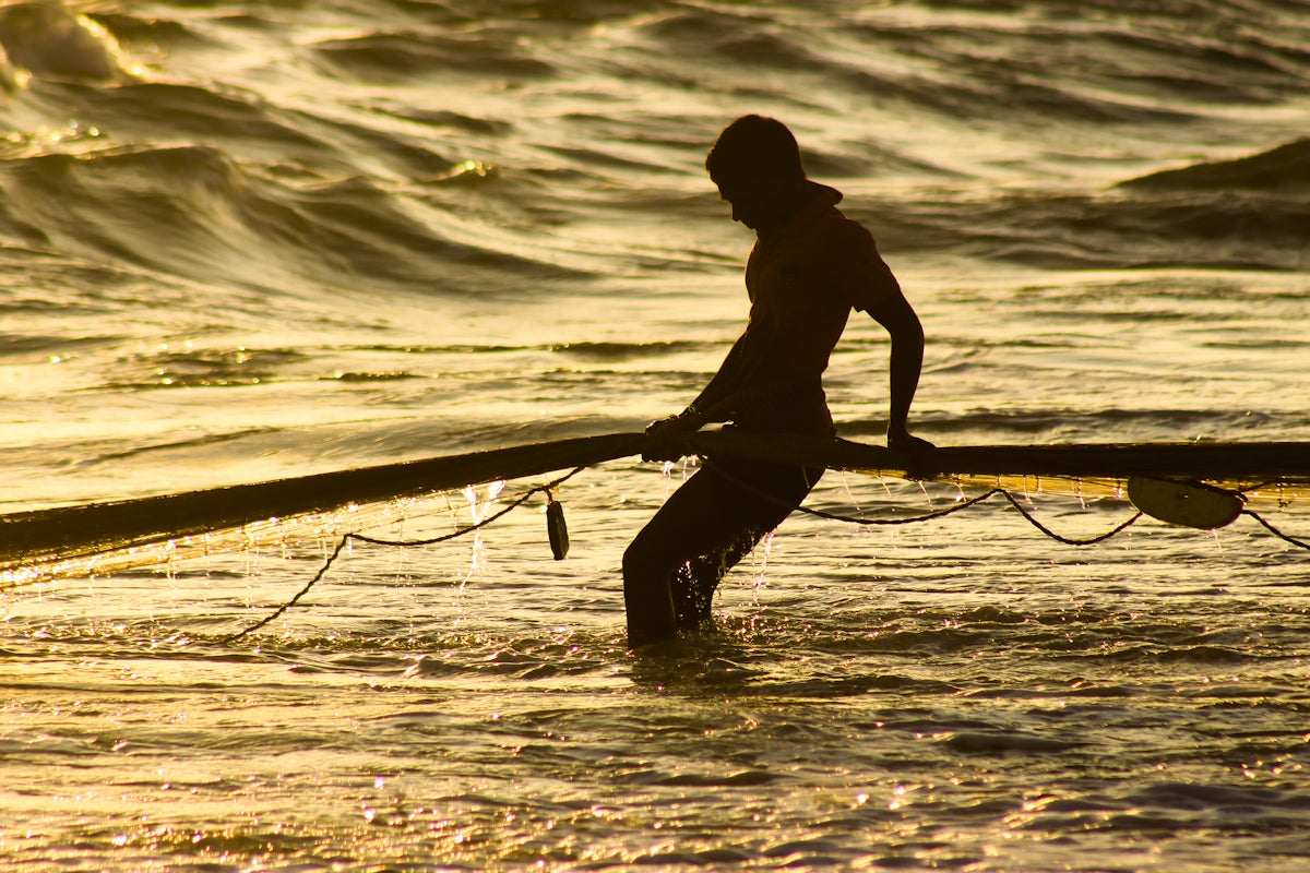man in black shorts holding a surfboard on the sea