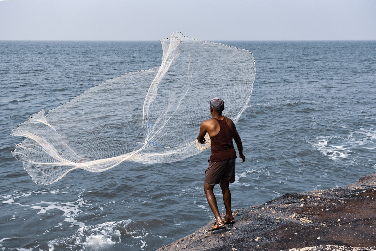 a man standing on top of a rock next to the ocean