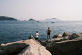 a man sitting on a rock next to a body of water