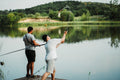 a couple of men standing on top of a pier next to a lake