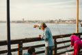 a man standing on a pier holding a fishing rod