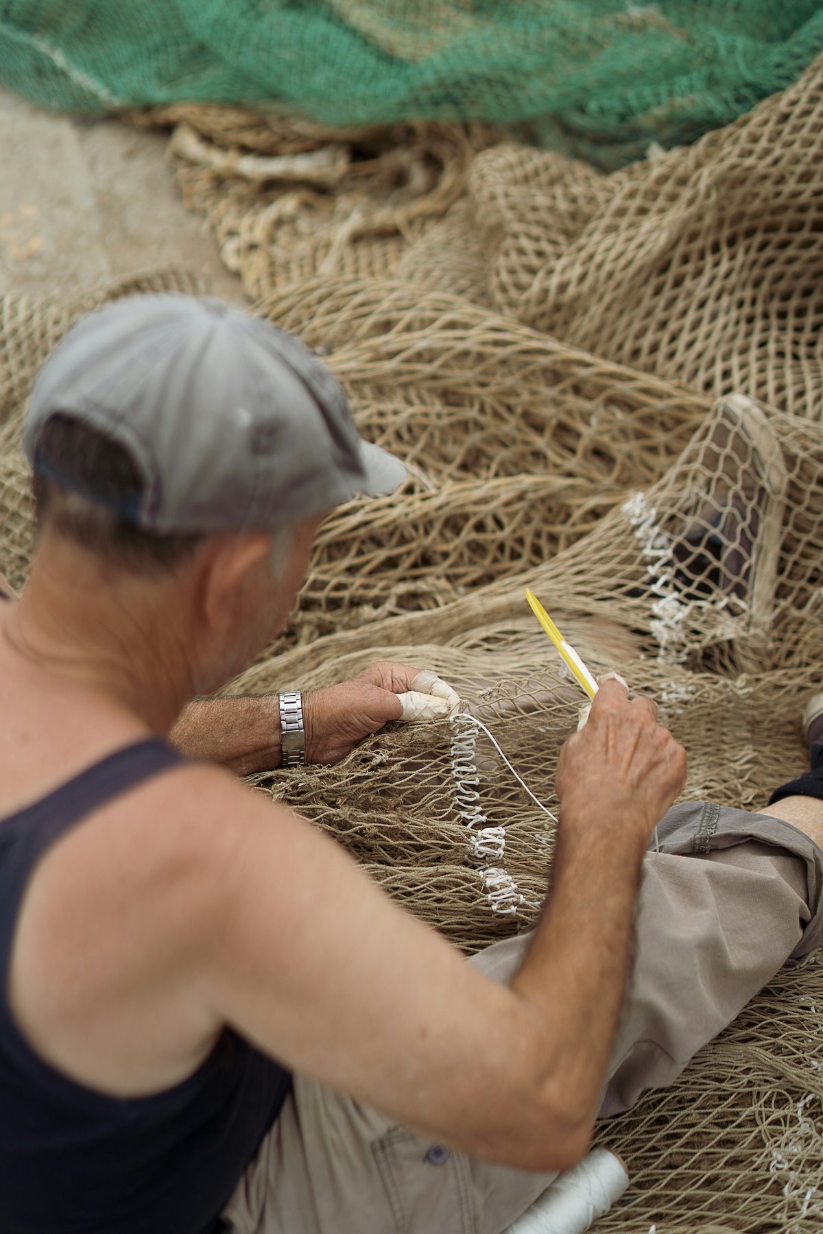 A man sitting on a beach next to fishing nets