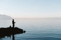 A man standing on a rock in the middle of a body of water