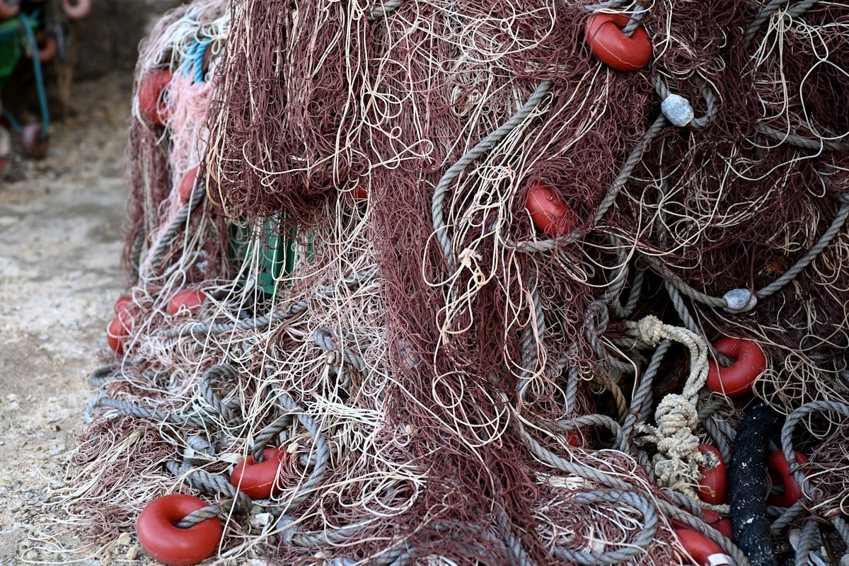 Tangled fishing net with red buoys piled on top.