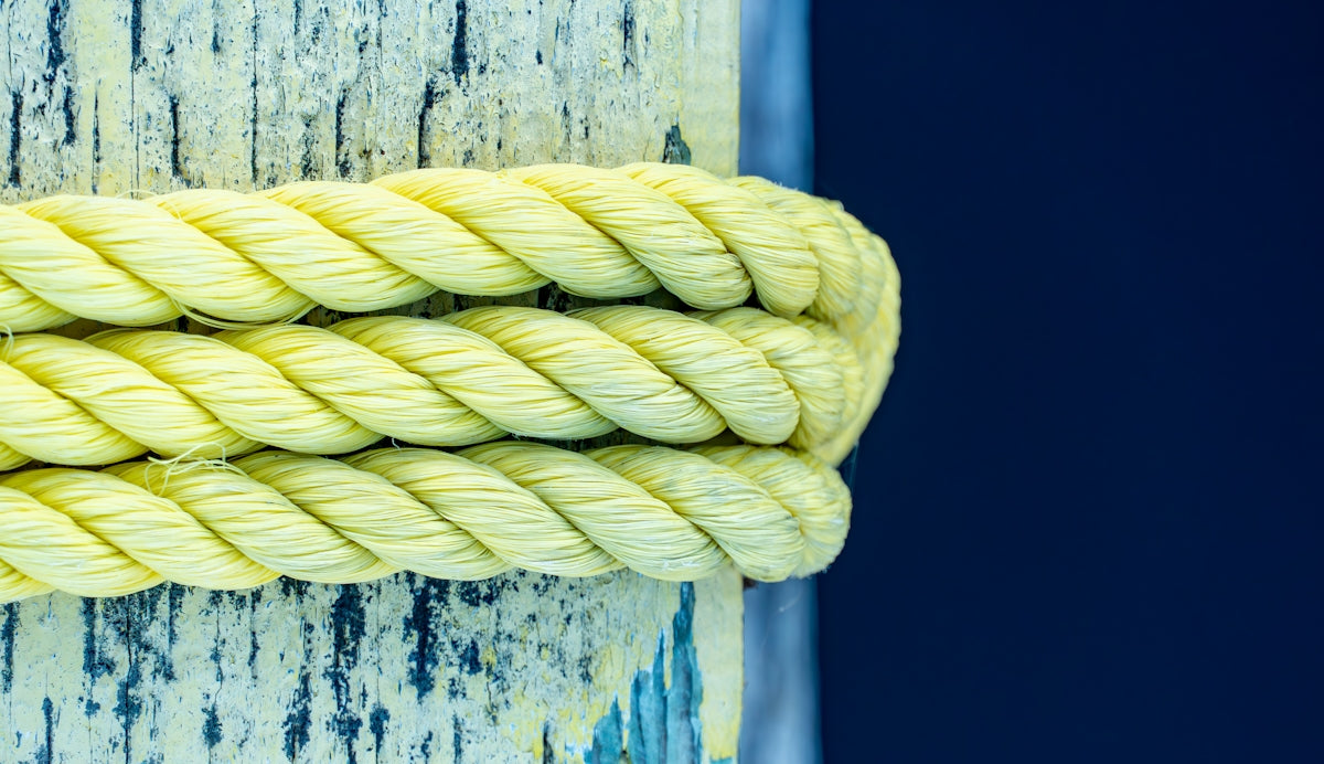 Yellow rope is wrapped around a wooden post.