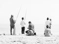 Family fishing together on a sandy beach.