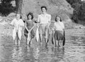 Four people stand in water holding fish