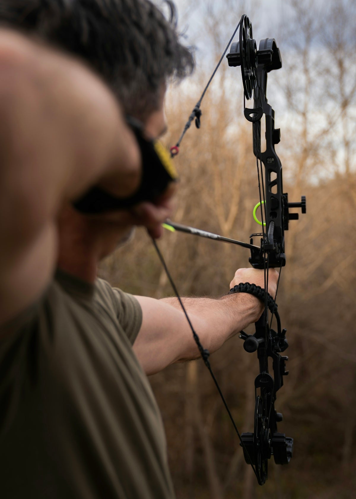 A person aiming a PRO HUNTER HAND CASTER bow in the outdoors, highlighting precision and skill.