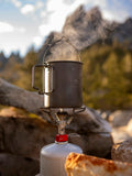 Steam rises from a camping pot on a portable stove.