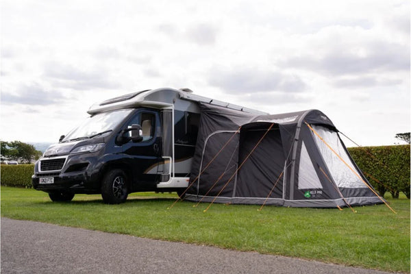 Vango Kela Pro Air Tall Drive Away Awning attached to a campervan on a grassy area, showcasing outdoor living space.
