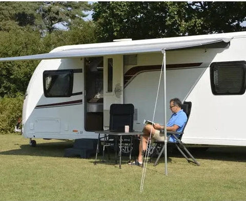 Man reading outside a caravan.