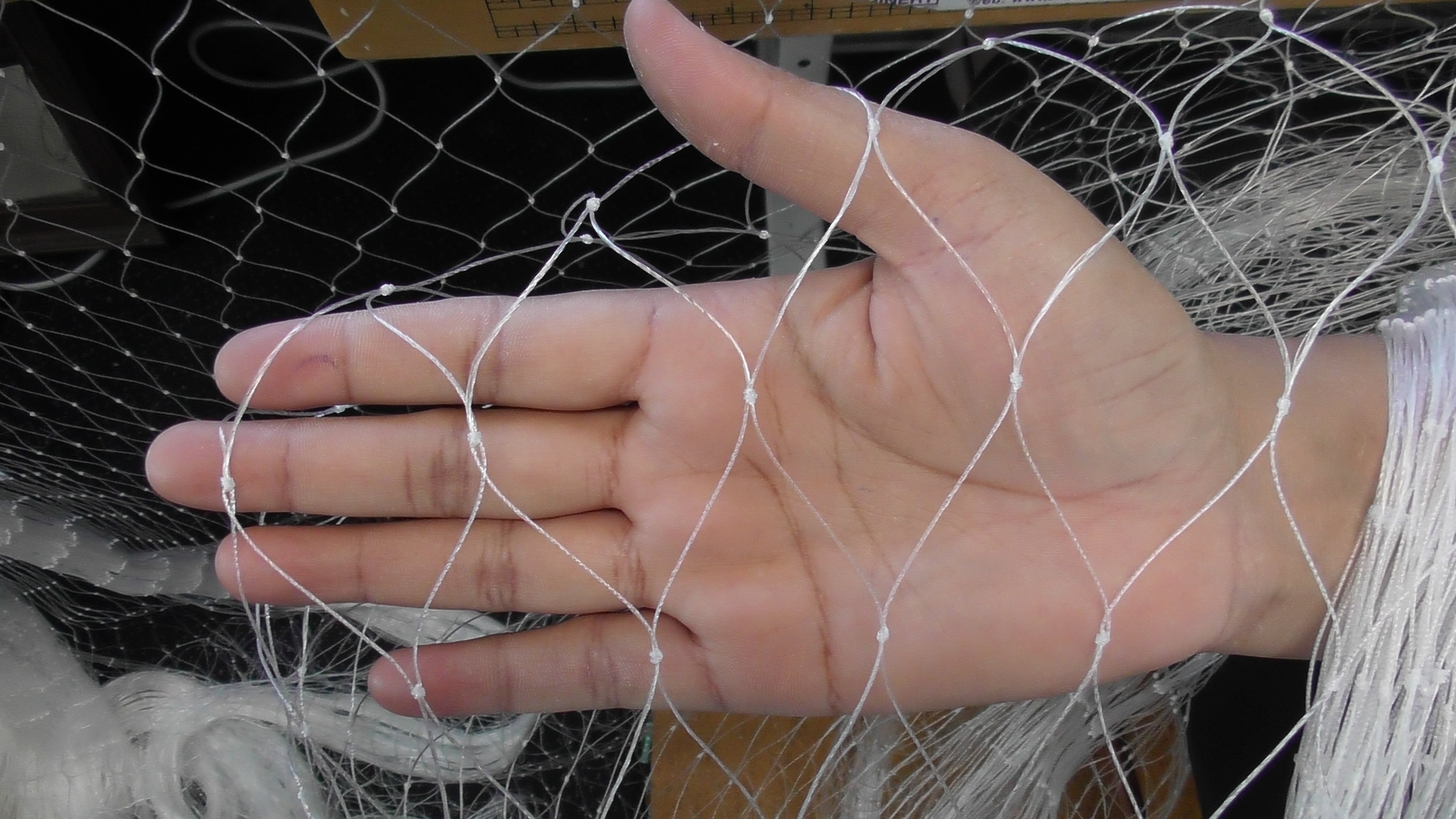 Hand holding NZ Made Mullet and Snapper Fishing Nets Multi Mono mesh showing intricate knotting and design.
