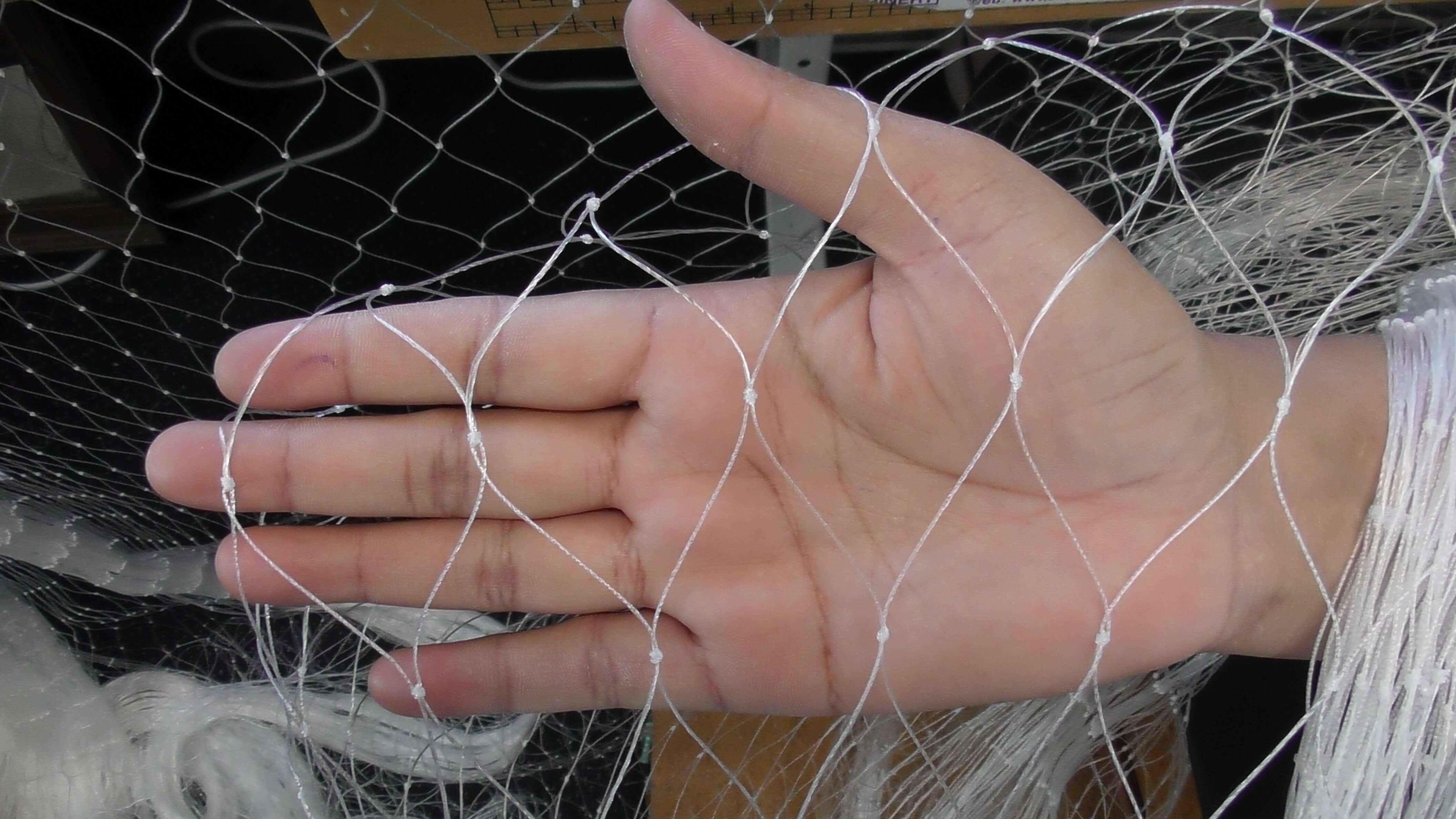 Hand holding NZ Made Mullet and Snapper Fishing Nets Multi Mono mesh showing intricate knotting and design.