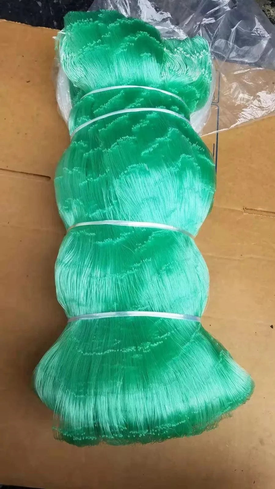 Green Mono Net 0.9 x 6.5 inch x 15MD x 450m spool displayed on cardboard background