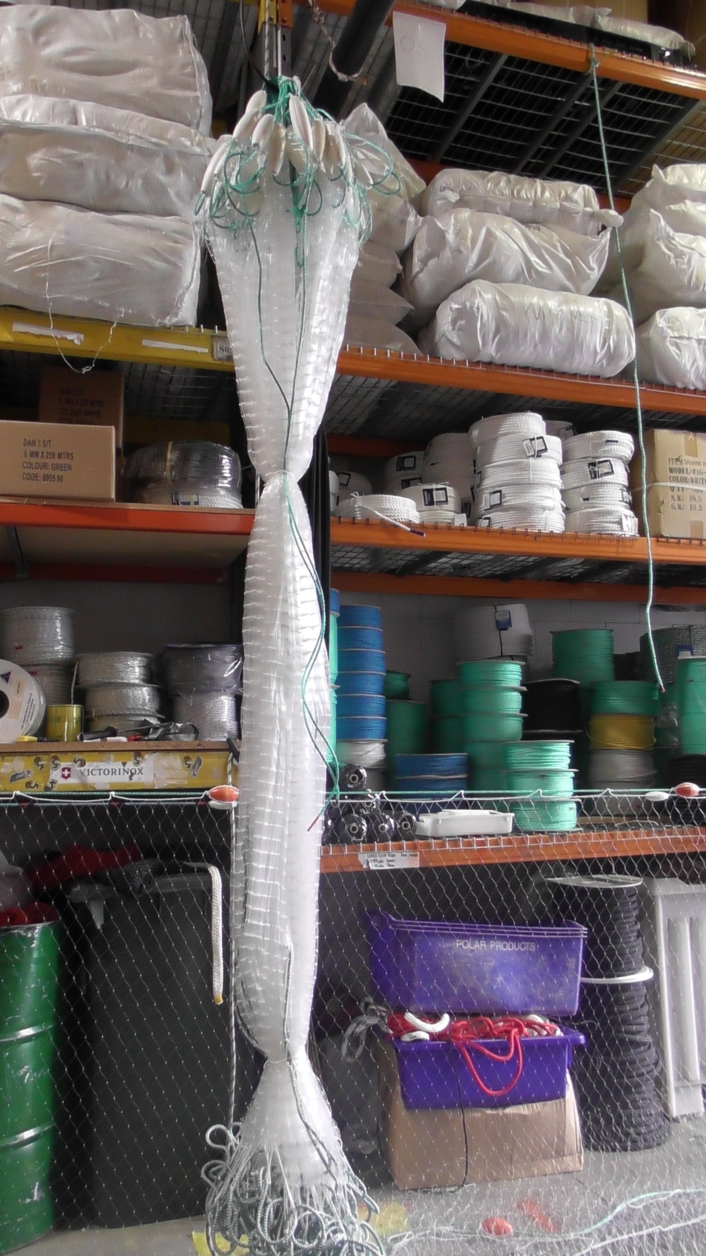 Strong 2-Inch x 0.60 mm Pacific Island Nets hanging in a warehouse, showcasing durability and quality for fishing.