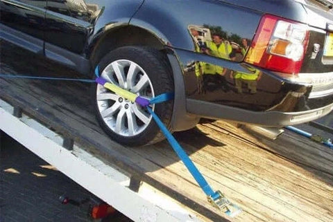 Vehicle tie-down straps securing a car on a ramp.