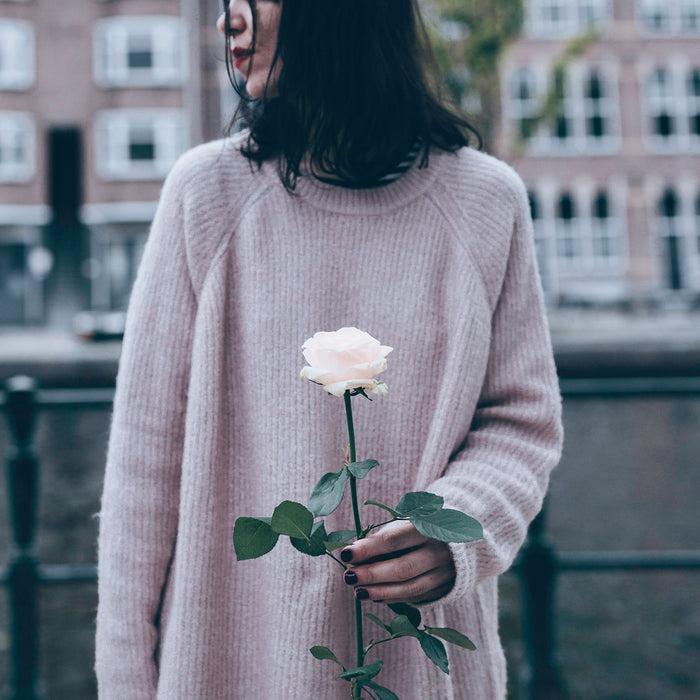 woman in white sweater holding white flower