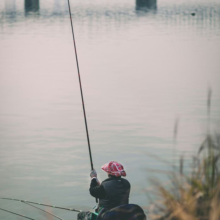 person holding fishing rod beside body of water