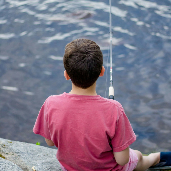 boy fishing on body of water