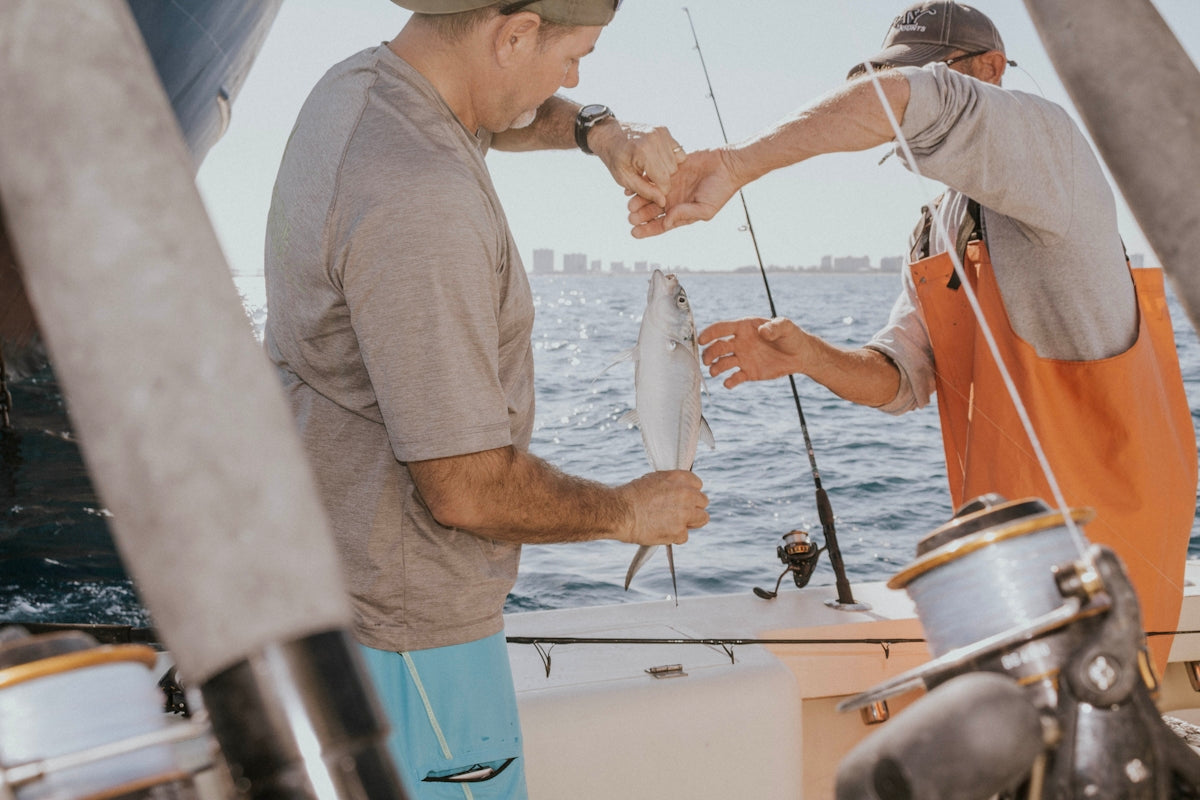 photography of man holding fish during daytime