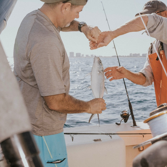 photography of man holding fish during daytime