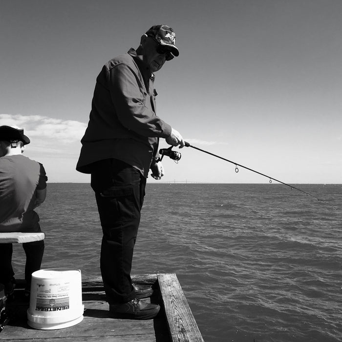 man in black jacket and pants fishing on sea