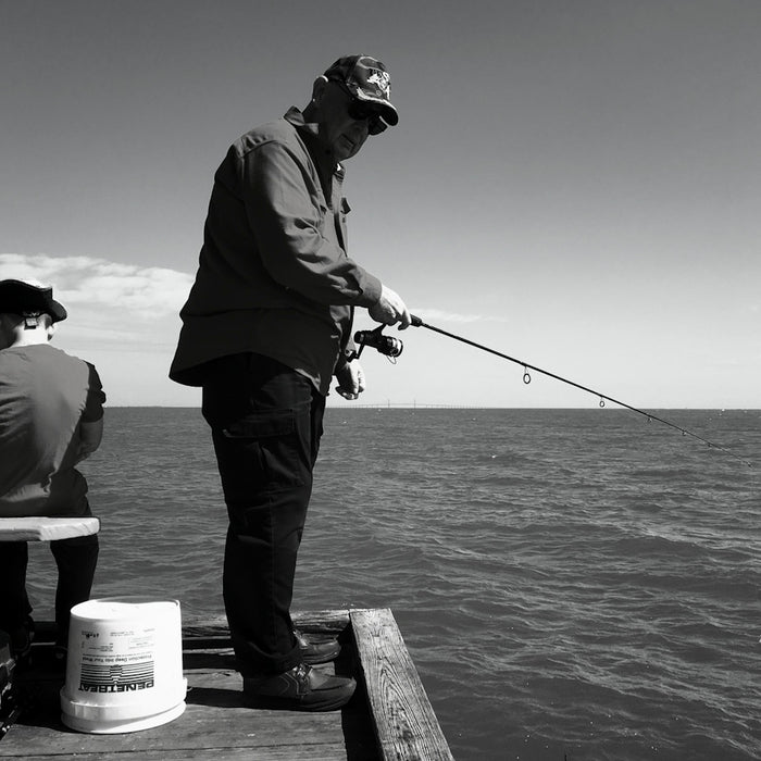 man in black jacket and pants fishing on sea