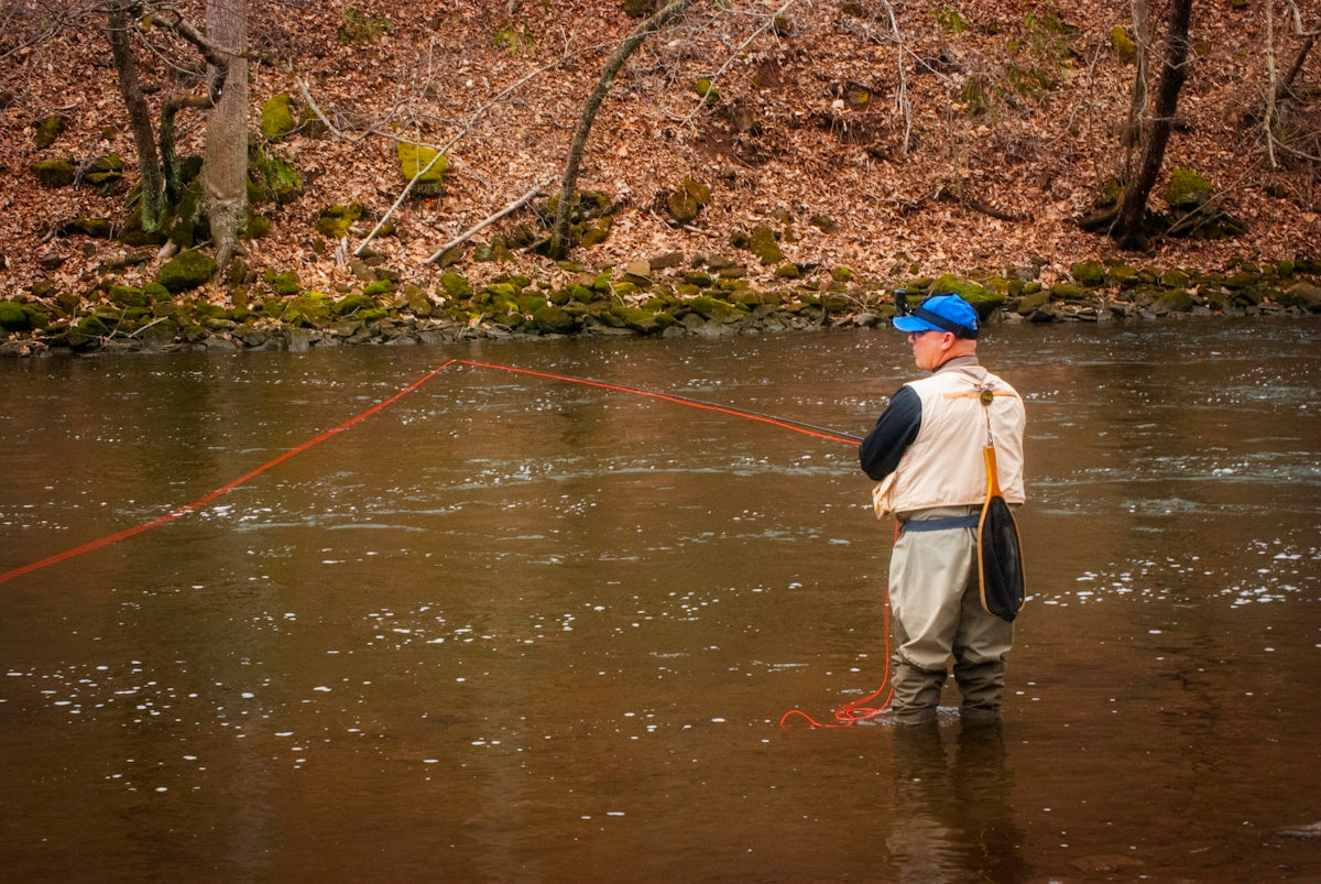 woman in brown jacket and brown skirt fishing on river during daytime