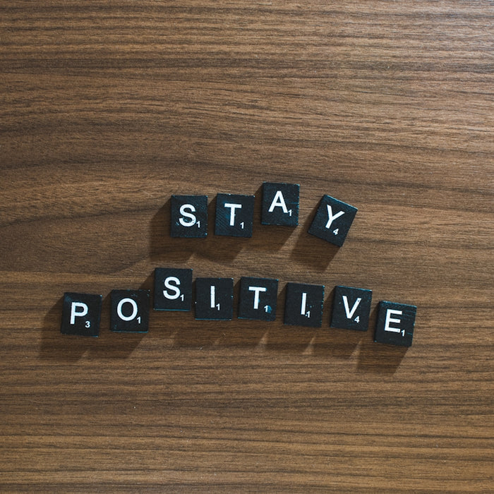the word stay positive spelled in scrabble type on a wooden surface
