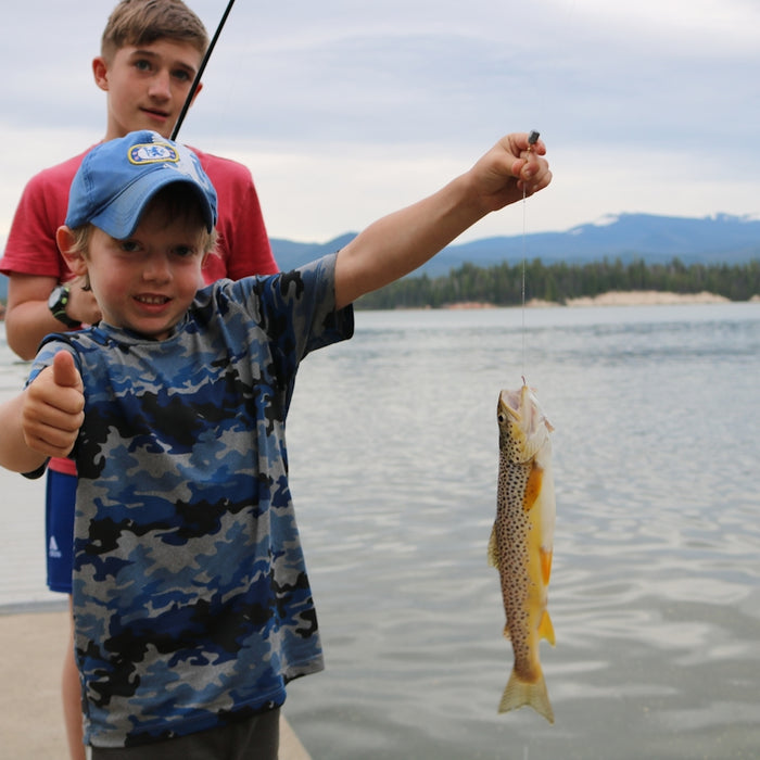 boy in blue and white camouflage shirt holding fish