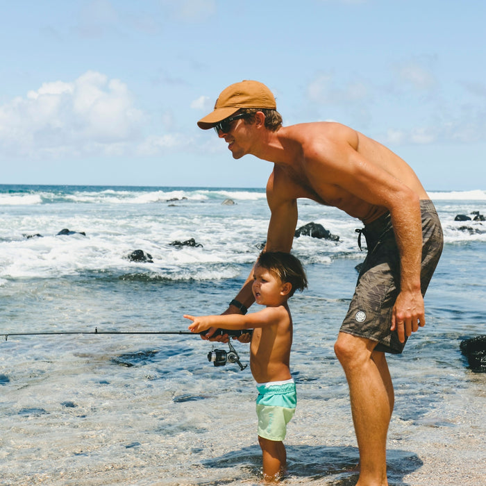 man in blue shorts and brown hat running on beach during daytime
