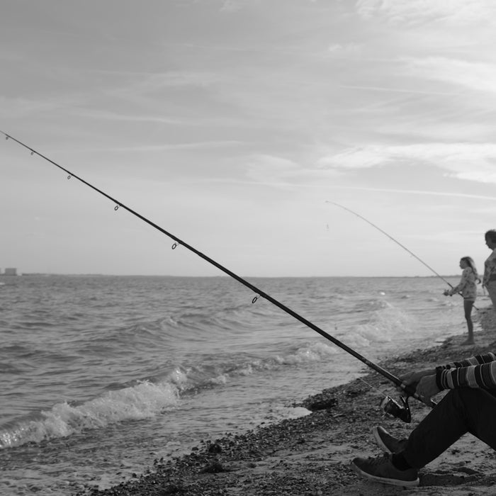 grayscale photo of 2 men fishing on sea