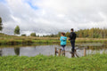 man in black jacket and blue denim jeans standing on brown wooden dock during daytime