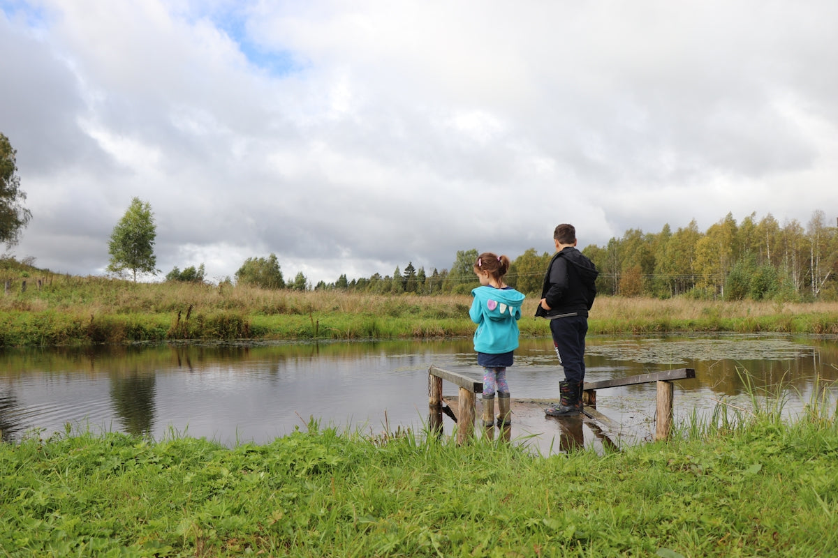 man in black jacket and blue denim jeans standing on brown wooden dock during daytime