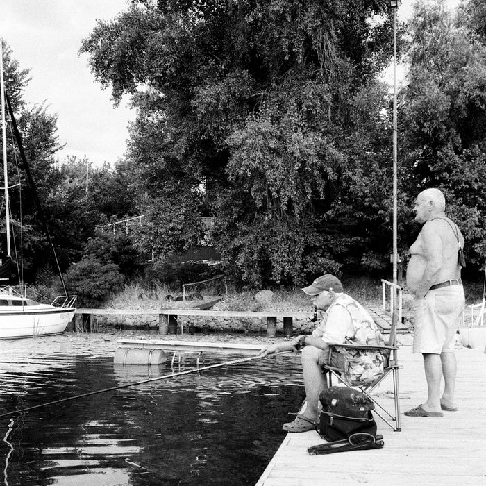 man in white shirt sitting on bench near river