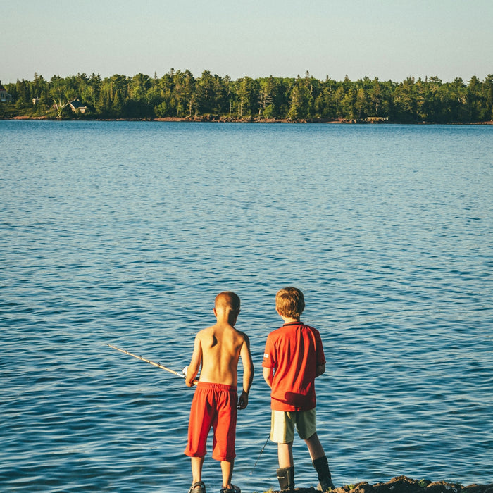 2 boys standing on body of water during daytime