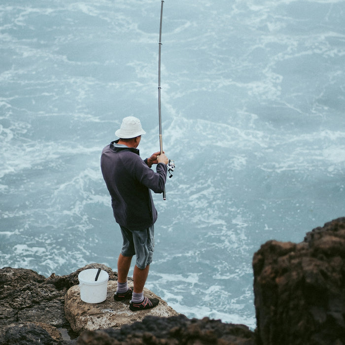man in black jacket fishing on sea during daytime