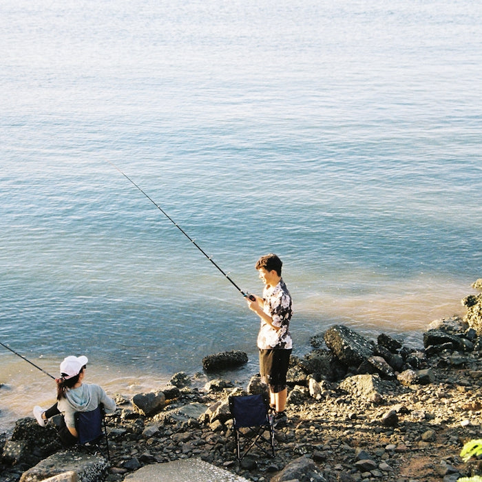 woman in white shirt and black pants fishing on sea during daytime