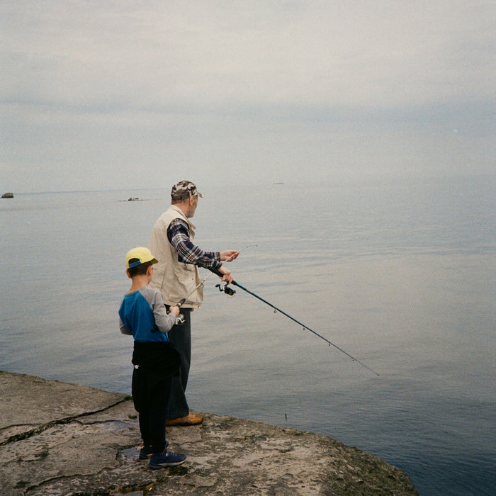 a man holding a fishing rod while standing next to a little boy