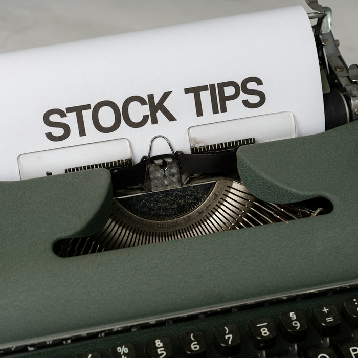 a close up of an old fashioned typewriter with a paper that reads stock tips