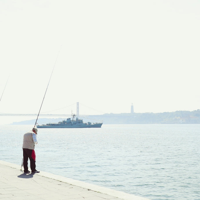 a man standing on a pier holding a fishing pole