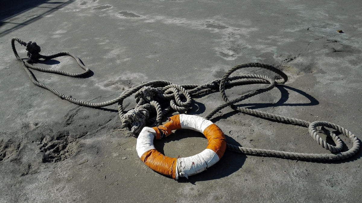 Longline anchor rope buoy combination tips with anchored buoy and coiled rope on the beach.