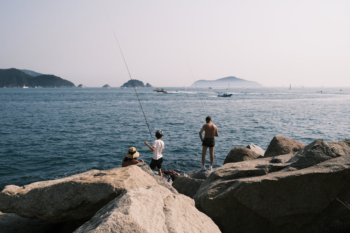 a man sitting on a rock next to a body of water