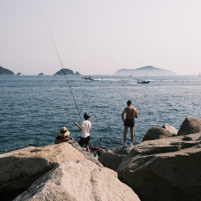 a man sitting on a rock next to a body of water