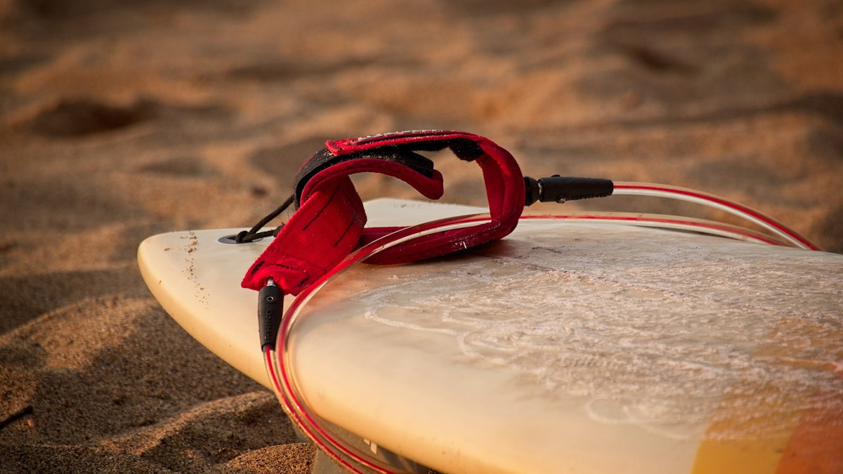 Exploring the Pro Hunter Surf Tackle Kit 65Pc with red surfboard leash on sandy beach.